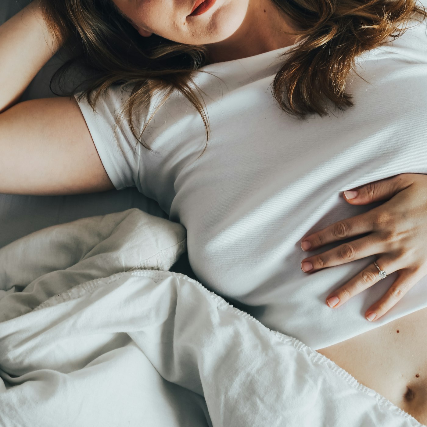 Donna incinta sdraiata a letto con la mano sulla pancia